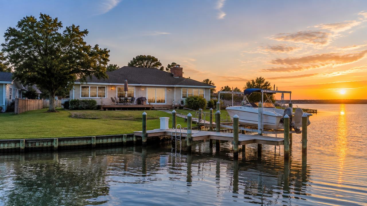 Waterfront ranch home with boat dock on an inlet at golden hour in Birdneck Point, Virginia Beach, Virginia