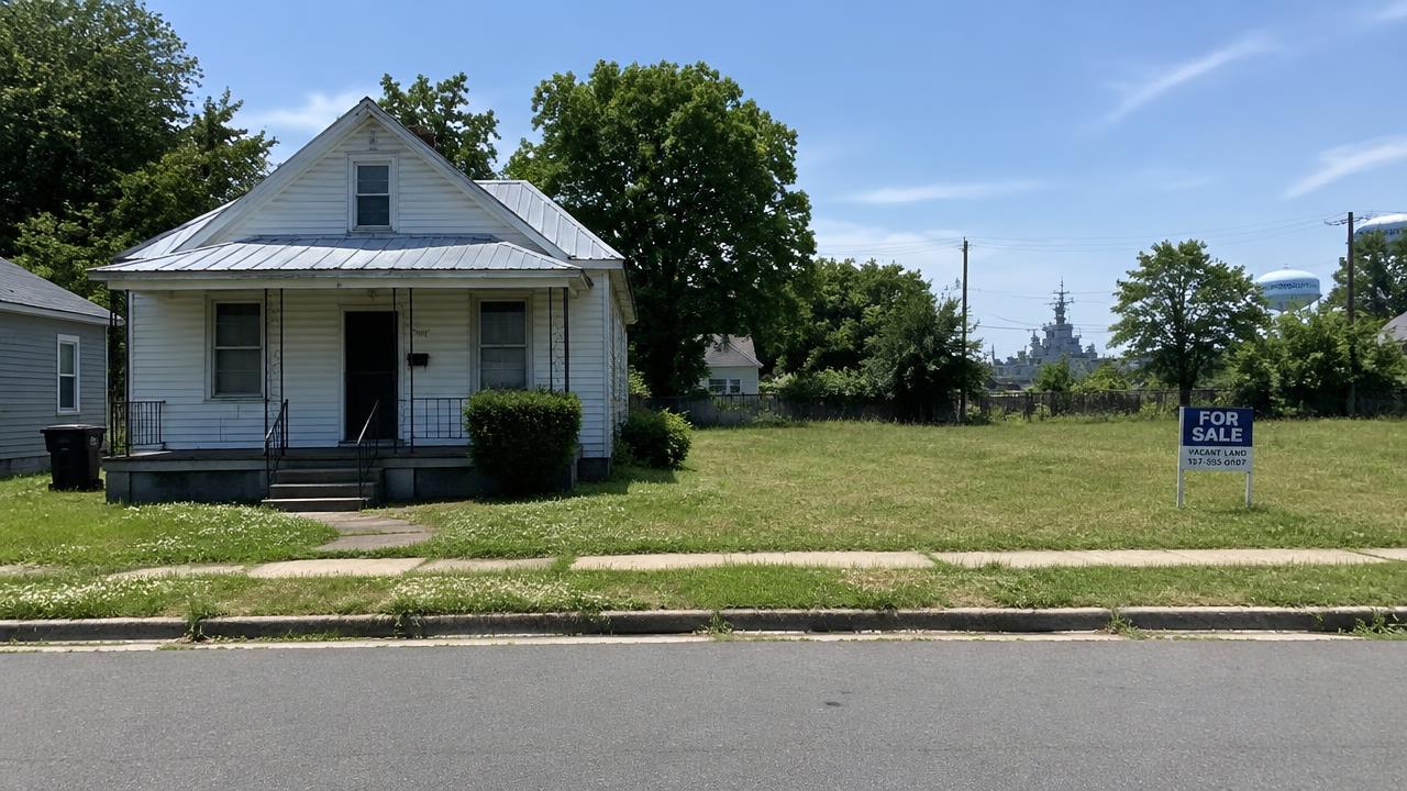 Small older frame house with a tin roof beside a vacant grassy lot in Emanuel, Portsmouth, Virginia