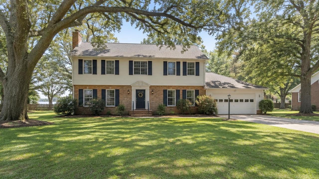 1970s two story colonial home with a large front yard and oak trees in Etheridge Manor, Chesapeake, Virginia