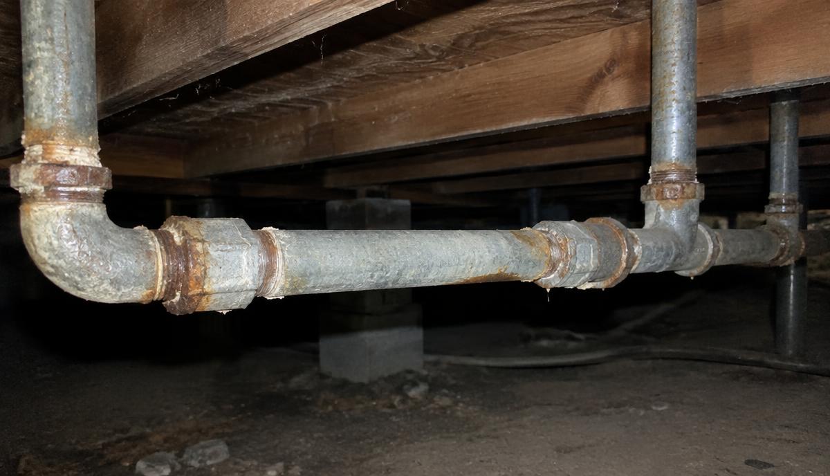 Corroded galvanized steel water pipes in the crawlspace of an older Virginia home