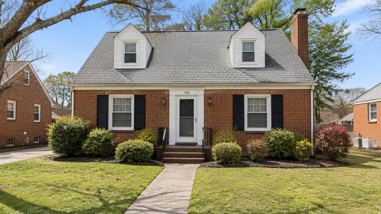 1950s brick cape cod home with dormers and a concrete walkway in Highland Biltmore, Portsmouth, Virginia